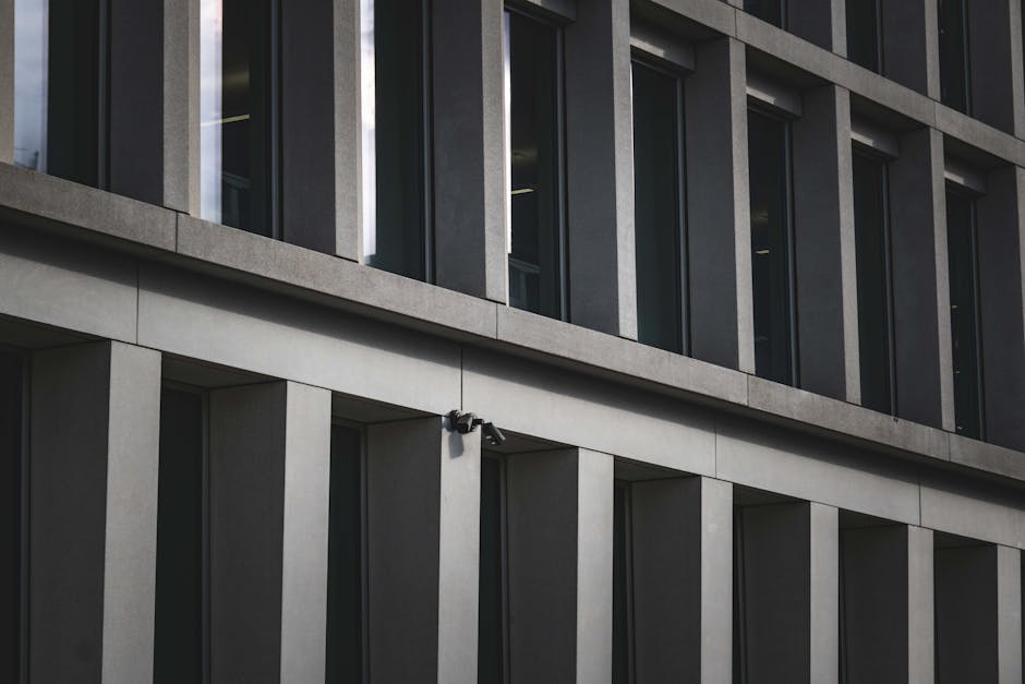Contemporary office building exterior featuring multiple windows and security cameras.