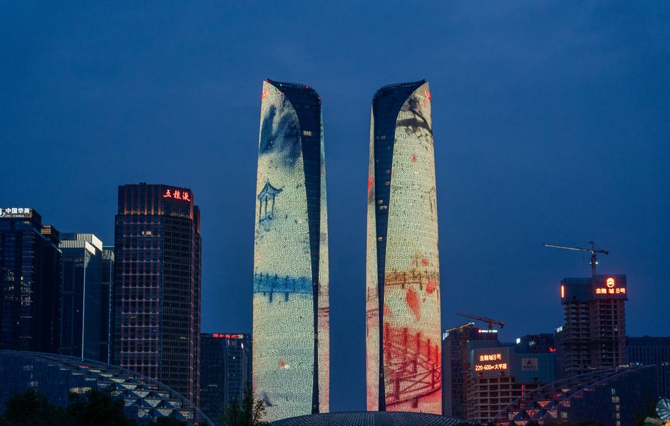 Night view of illuminated skyscrapers with artistic projections in a city skyline.